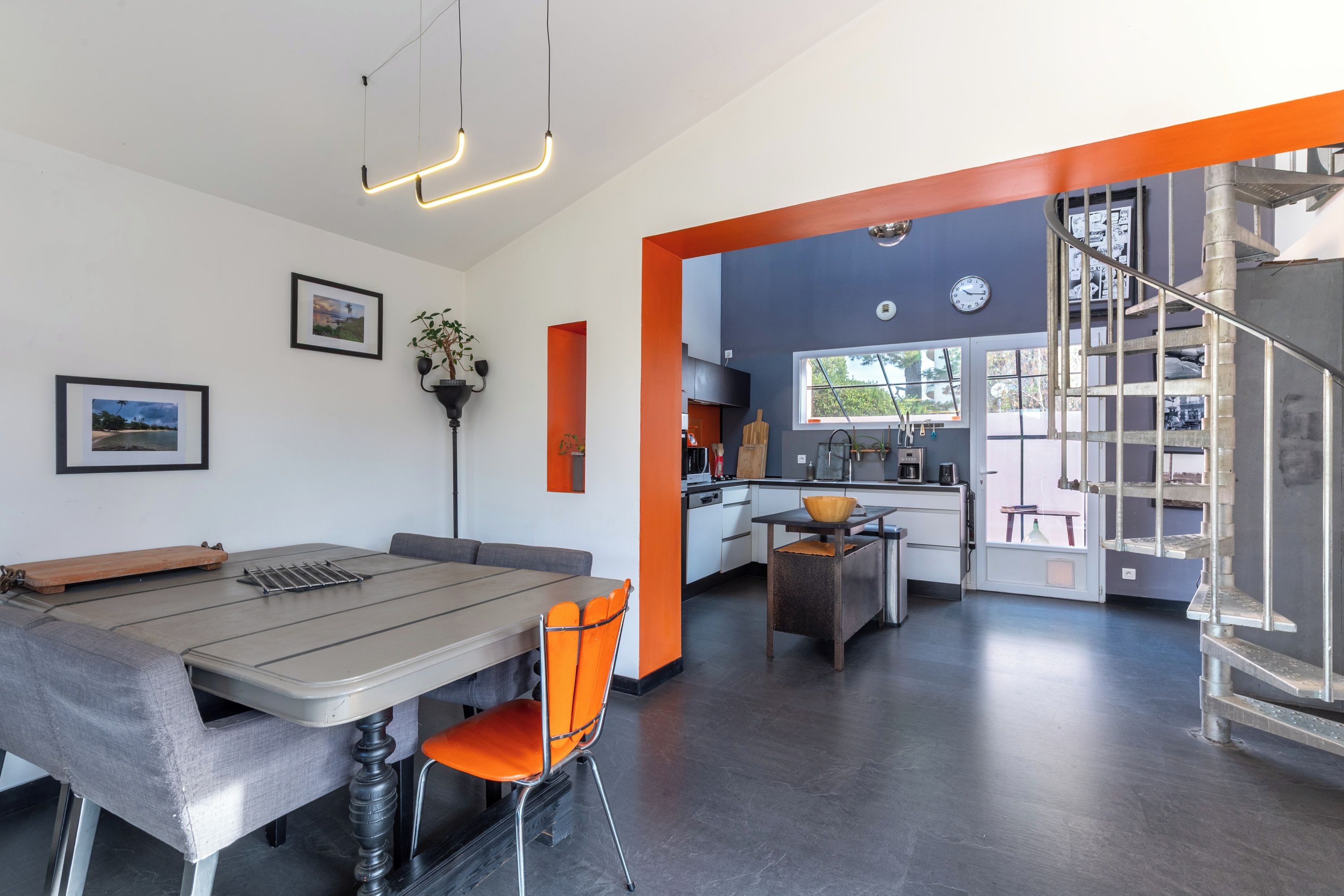 Una cocina moderna con comedor, una escalera y vistas al exterior.