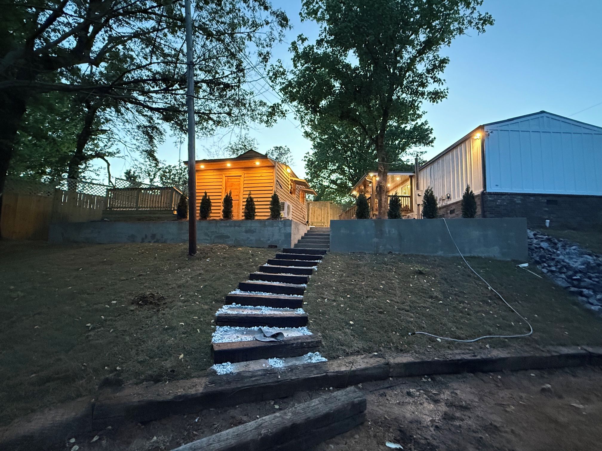 Eine Holzhütte mit einer Treppe, umgeben von Bäumen und einem eingezäunten Bereich.
