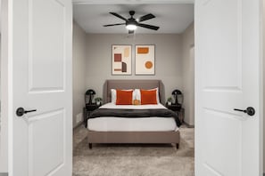 A bedroom with a bed, a ceiling fan, two bedside tables with lamps, and abstract wall art. - Duck Island 1BR , Walk to Ohio City + Parking (Cleveland)