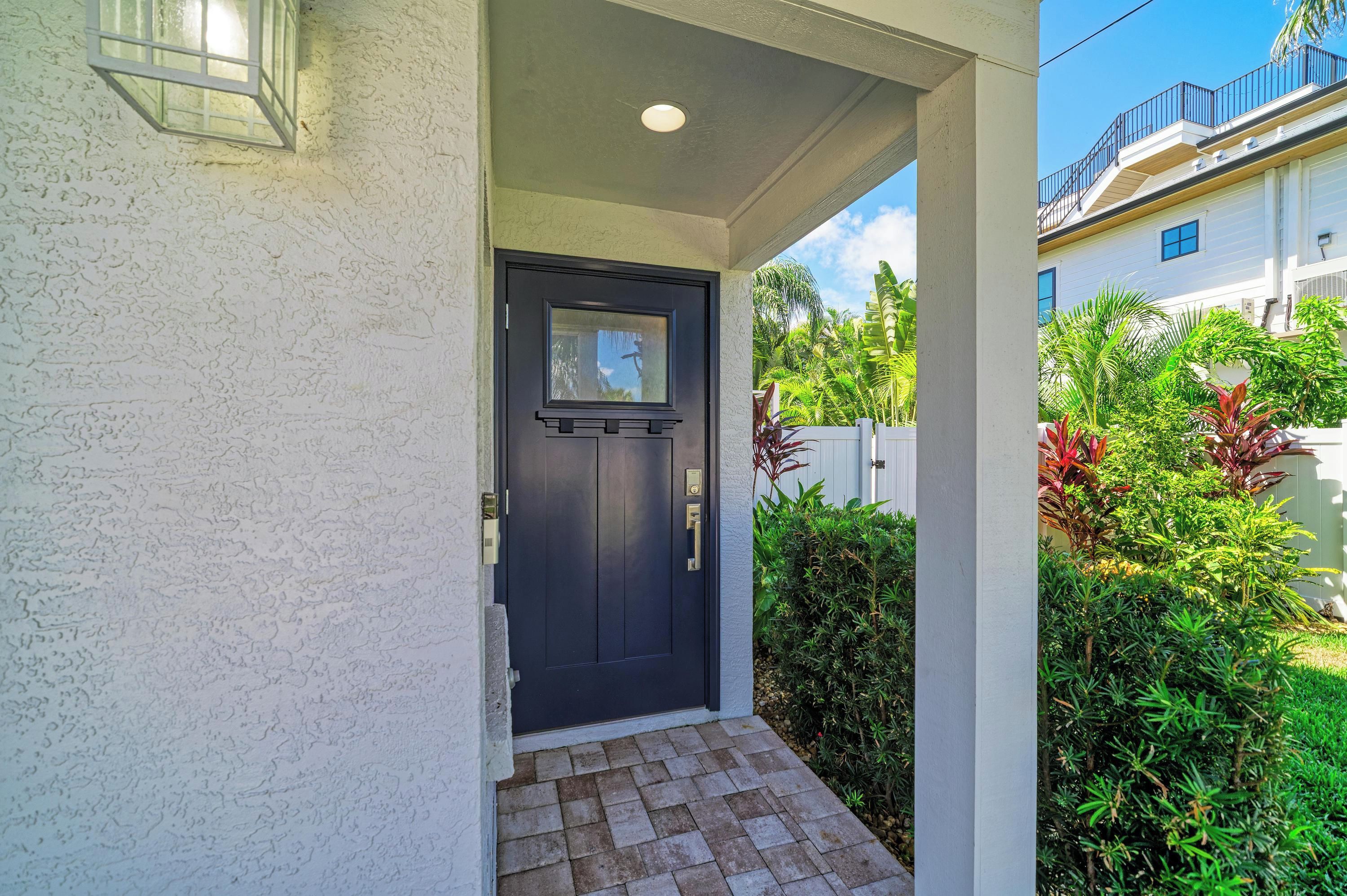 A house entrance with a dark door, a small porch, and a white exterior wall.