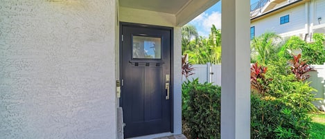 A house entrance with a dark door, a small porch, and a white exterior wall.