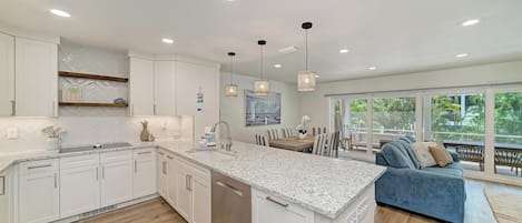 A modern kitchen with white cabinetry, a granite countertop, and pendant lighting.