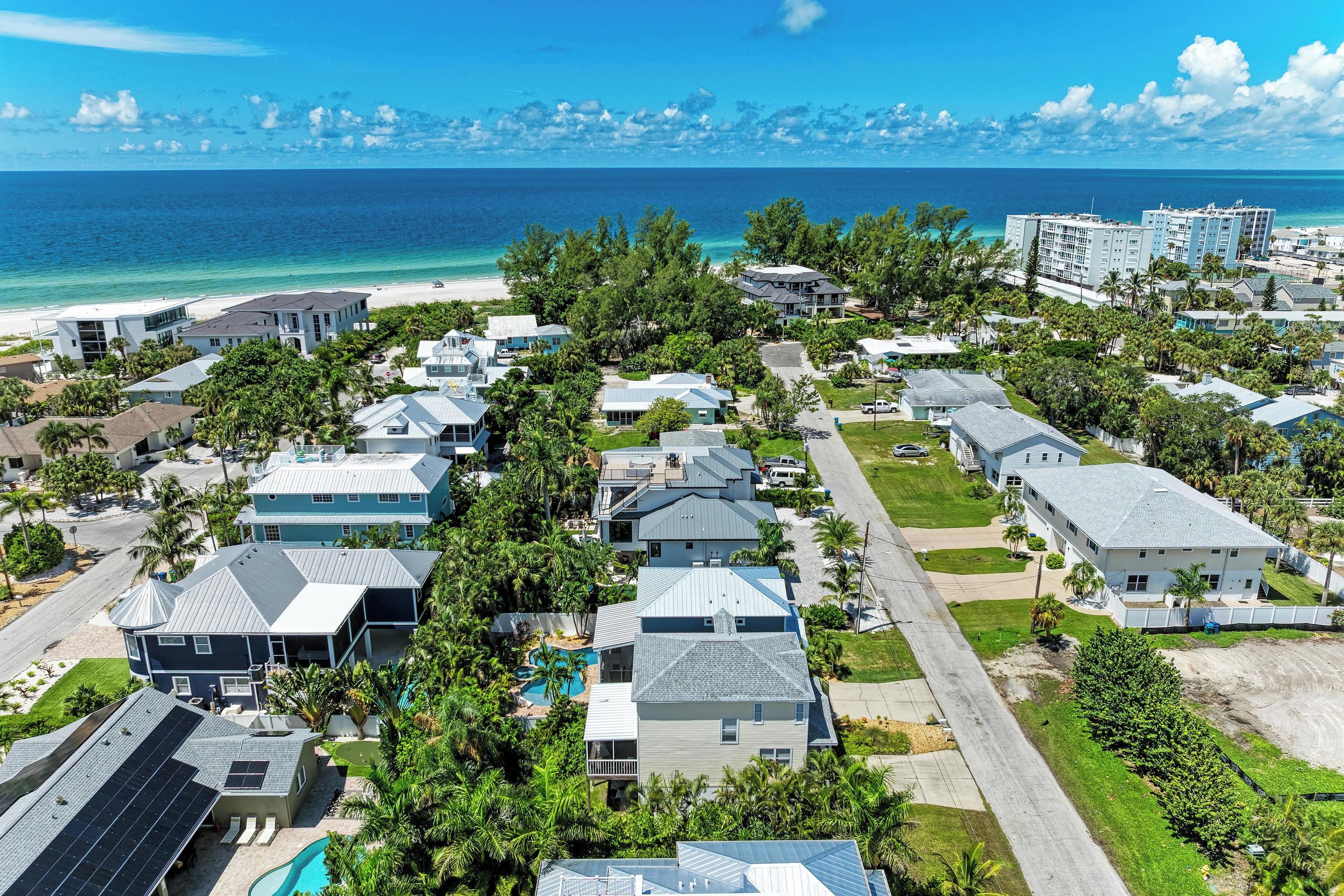 Uma área residencial costeira com casas, uma praia e vista para o oceano.