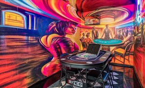 Ein Casino-Innenraum mit einem Roulette-Tisch, einem Blackjack-Tisch und einem Spielautomaten.