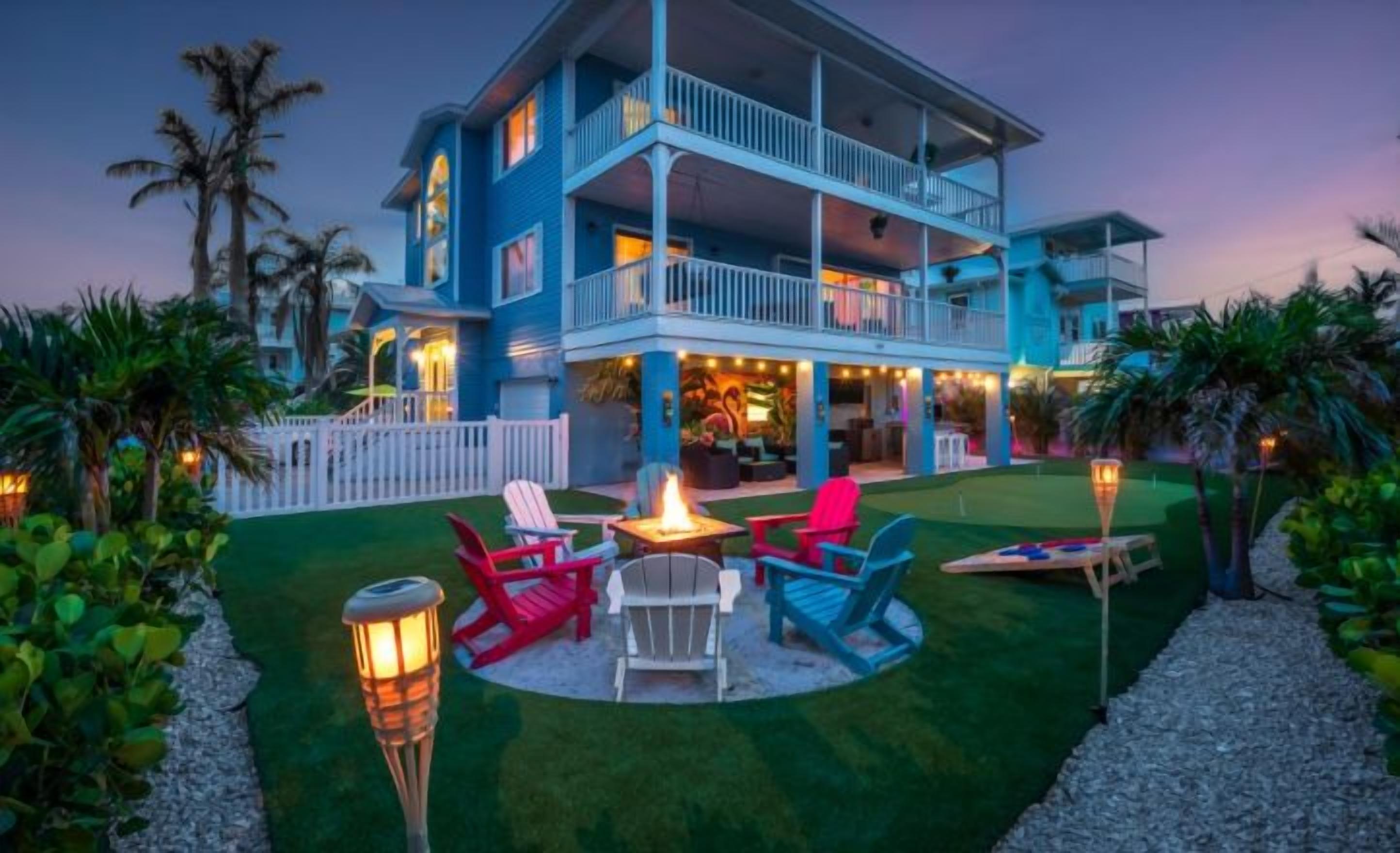 A two-story building with a balcony, outdoor seating area with chairs, and a small fire feature.