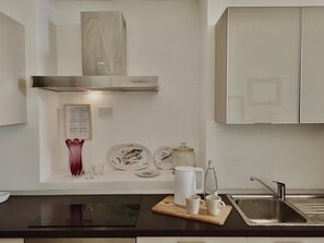 Une cuisine moderne dotée d’une hotte en acier inoxydable, de meubles blancs et d’un plan de travail noir.
