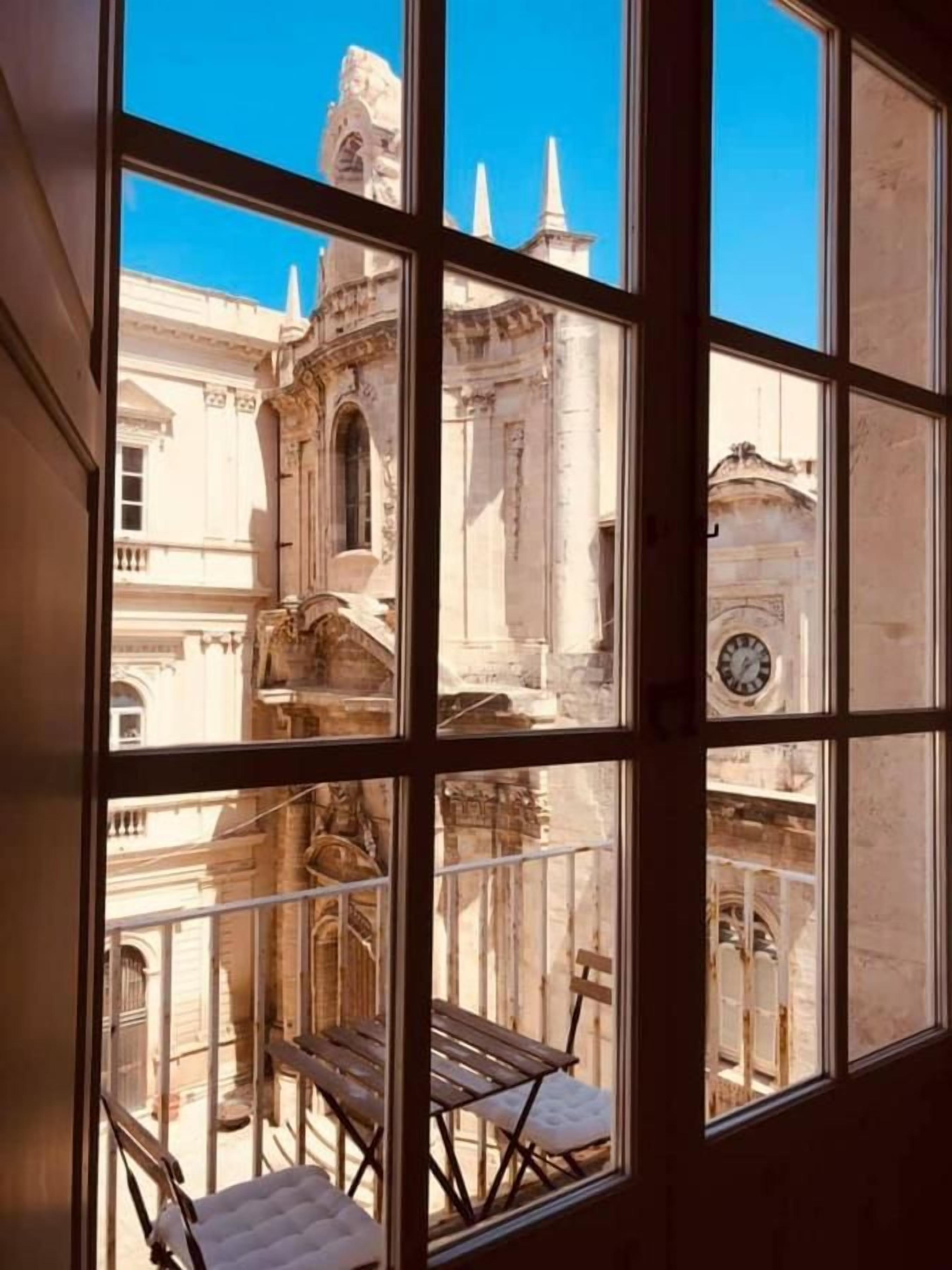 A room with a large window overlooking a historic building with classical architecture.