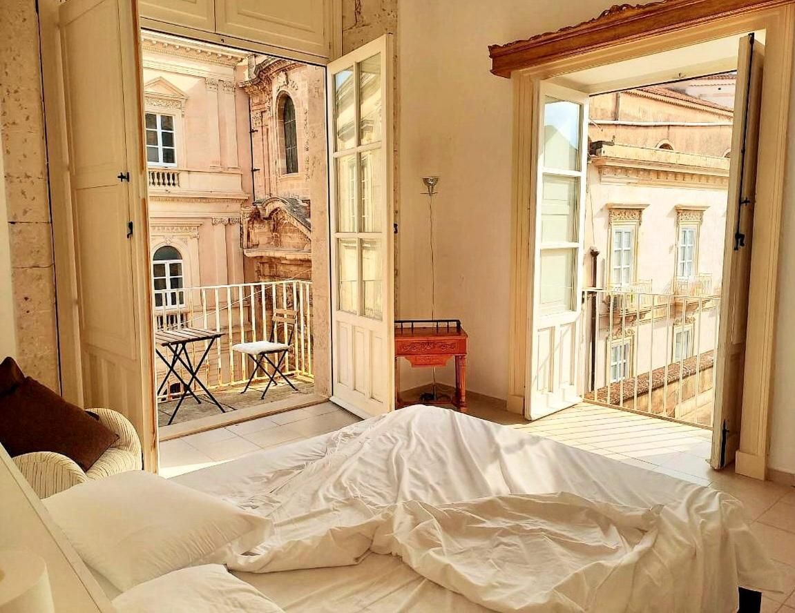 Ein Schlafzimmer mit Bett, einer Couch und einem Balkon mit Blick auf Gebäude.