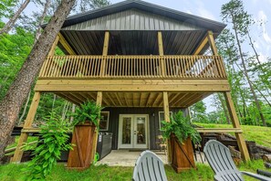 A two-story wooden cabin with a balcony, a front door, and a small porch area. - The Cozy Overlook: Cabin in Hocking Hills (Logan)