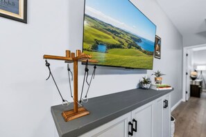 A flat-screen TV mounted on a wall above a grey console with a wooden stand holding glasses. - The Cozy Overlook: Cabin in Hocking Hills (Logan)