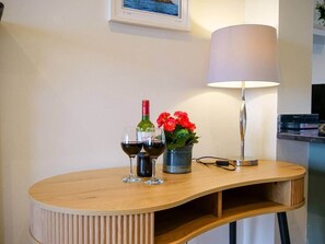 A wooden table with two wine glasses, a bottle, and a flower arrangement. - Rose Cottage Dingle Town - Stunning Views (Dingle)