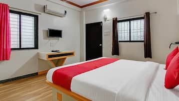 A hotel room with a bed, a desk, a television, and a window with curtains.