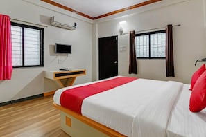 Ein Hotelzimmer mit Bett, Schreibtisch, Fernseher und einem Fenster mit Vorhängen.