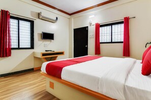 Ein Hotelzimmer mit Bett, Schreibtisch, Fernseher und einem Fenster mit Vorhängen.