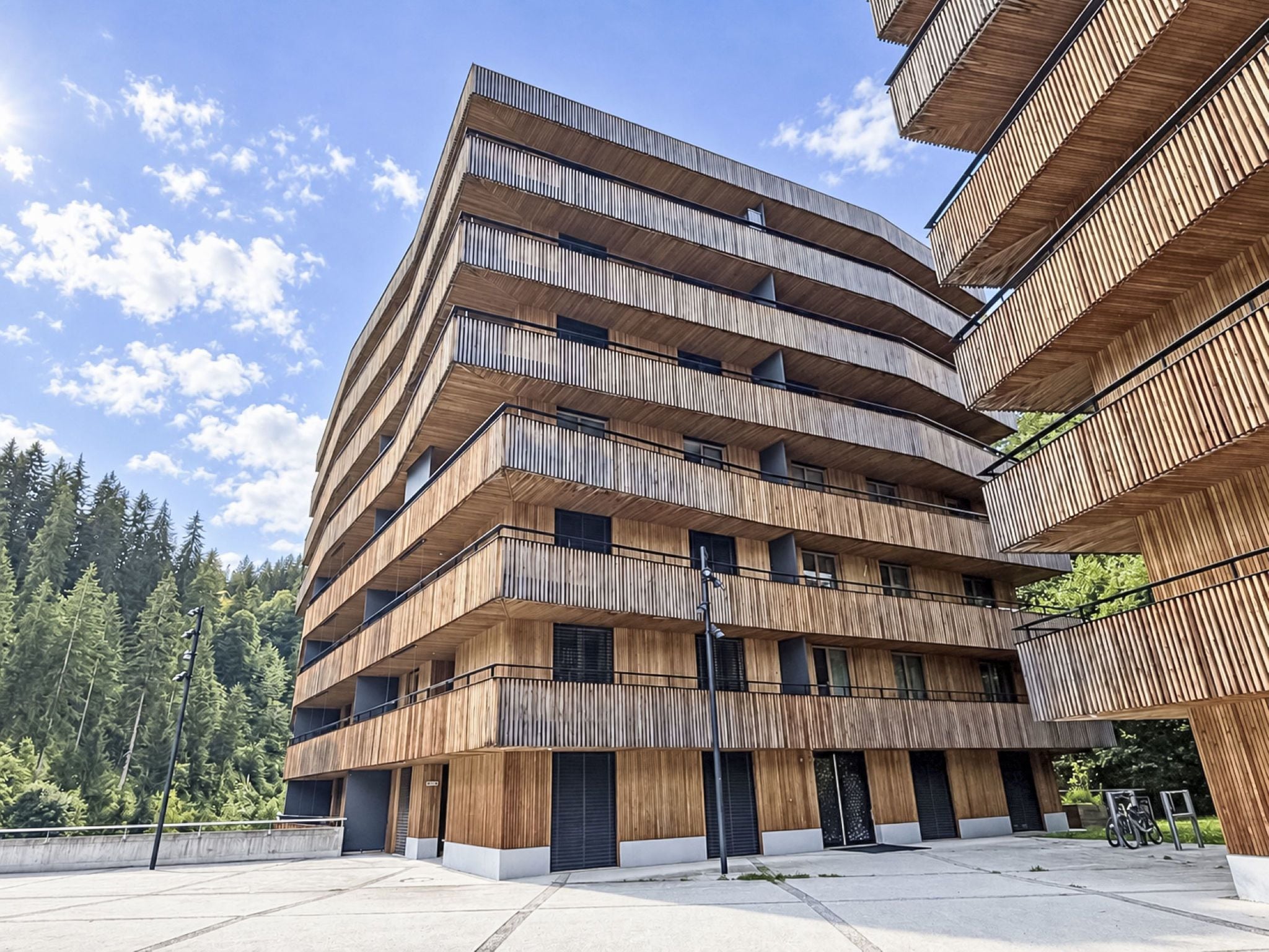 A multi-story building with a modern architectural design, featuring balconies and large windows.