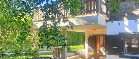 A two-story building with a balcony, outdoor seating, and a stone wall.