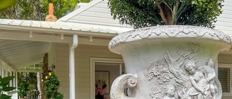 A white ornate urn with a tree and figures, placed on a brick patio.
