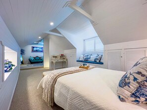 Un dormitorio con cama, escritorio, ventana y vista a otra habitación.