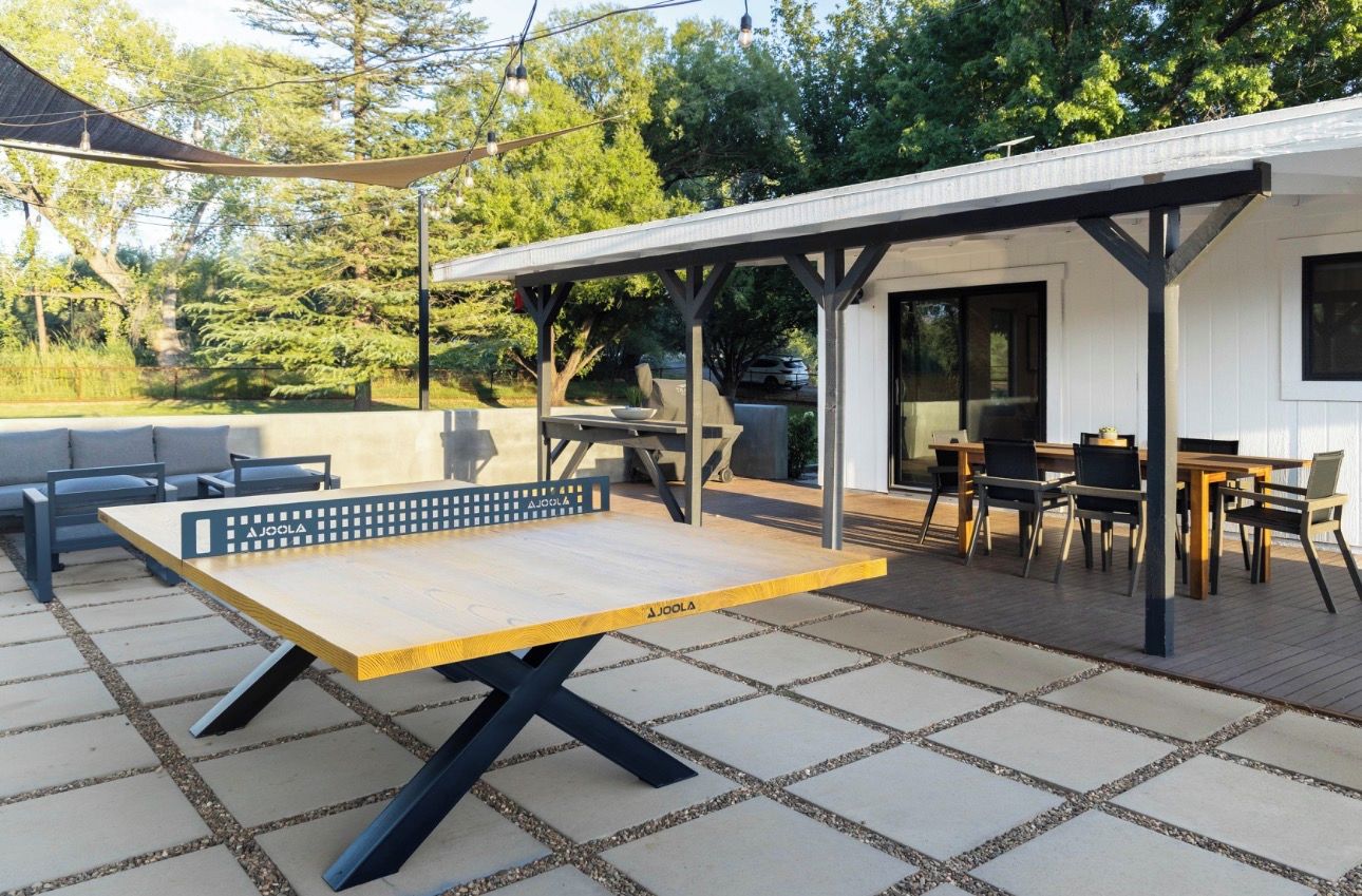 Une terrasse extérieure équipée d’une table de ping-pong, d’un espace salon et d’une partie abritée avec des tables et des chaises.