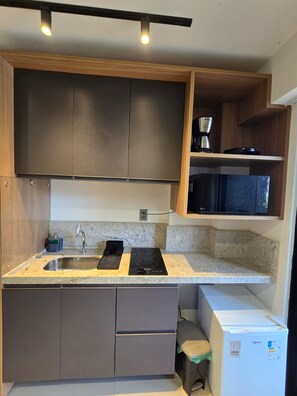 A compact kitchen with a built-in microwave, a coffee maker, and a small refrigerator. - Luxury beachfront apartment with everything you need on the same block. (João Pessoa)