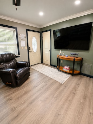 A living room with a leather sofa, a flat-screen TV, a wooden coffee table, and a patterned rug. - Fully remodeled home, with a fully stocked kitchen for those family gatherings. (Foley)