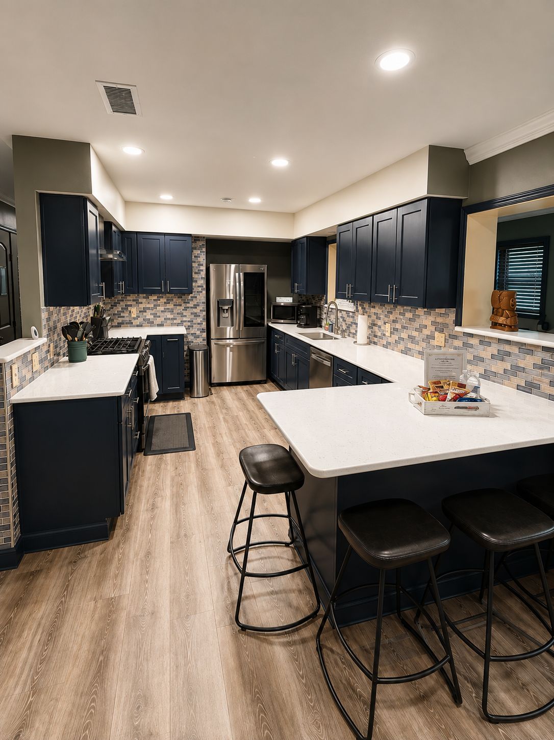 Una cocina moderna con armarios oscuros, un refrigerador de acero inoxidable, un microondas y una isla grande con taburetes.