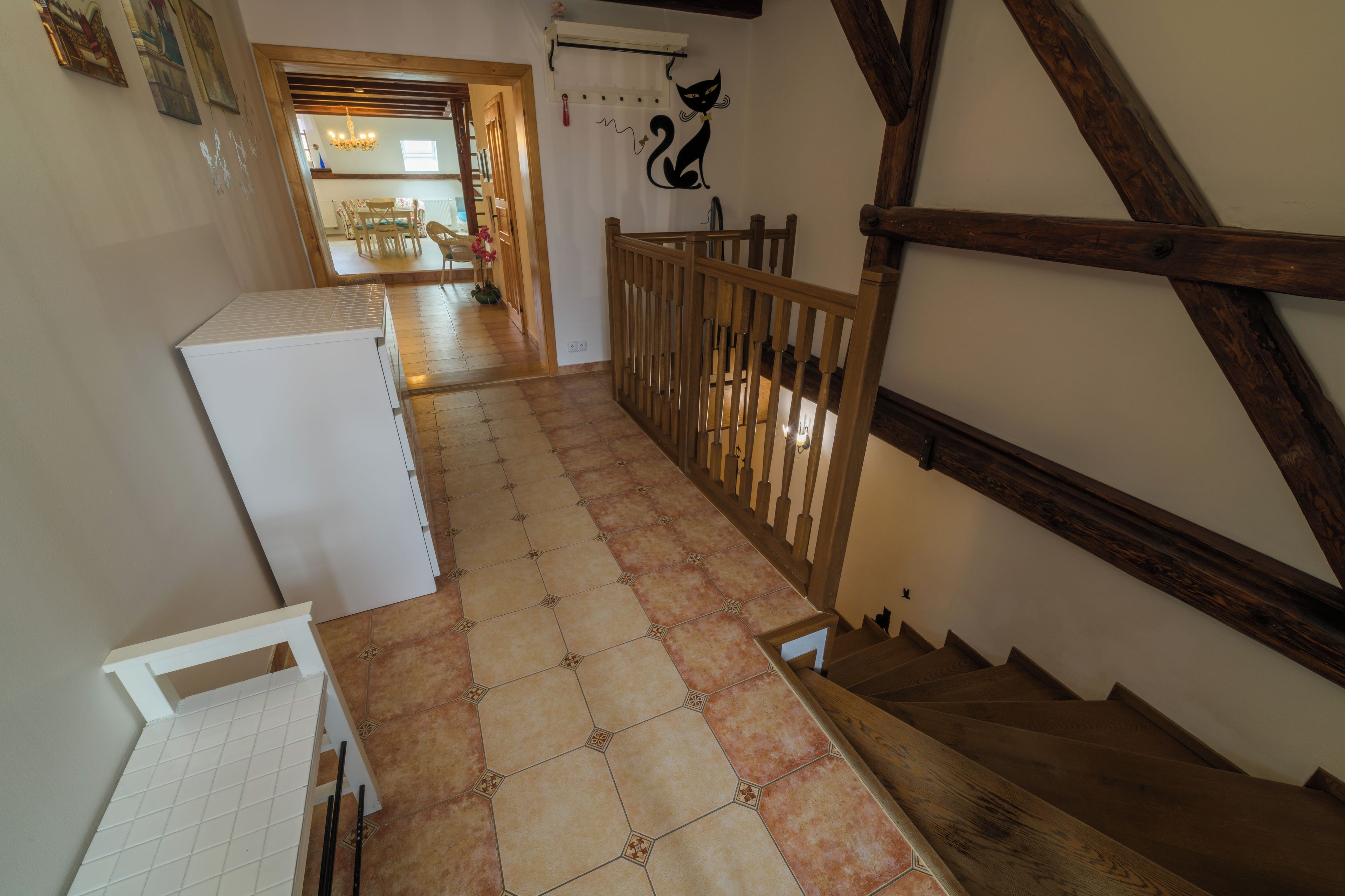 Un couloir carrelé qui mène à un escalier doté de rampes en bois.