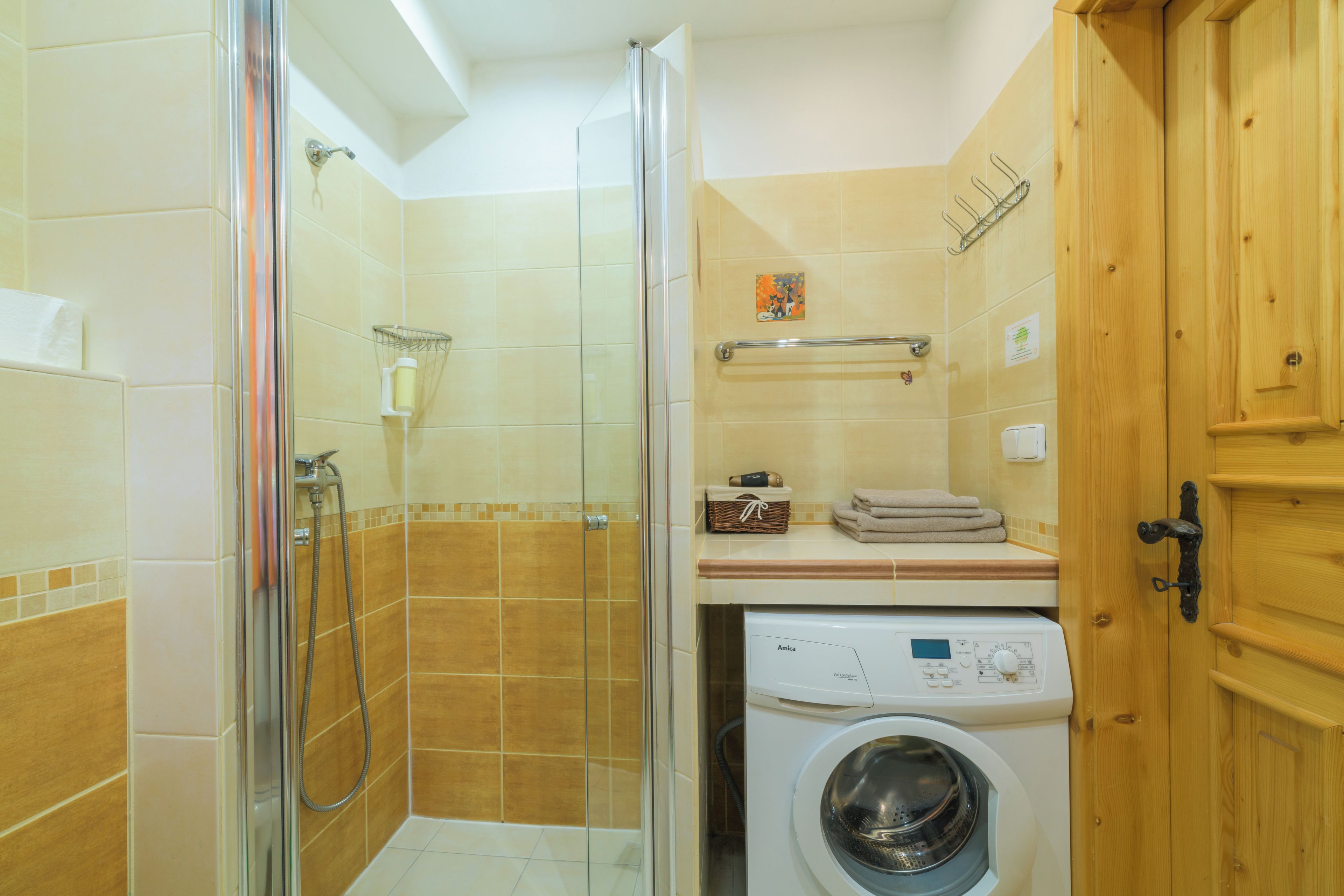 Un baño con cabina de ducha de vidrio, lavadora y armarios de madera.