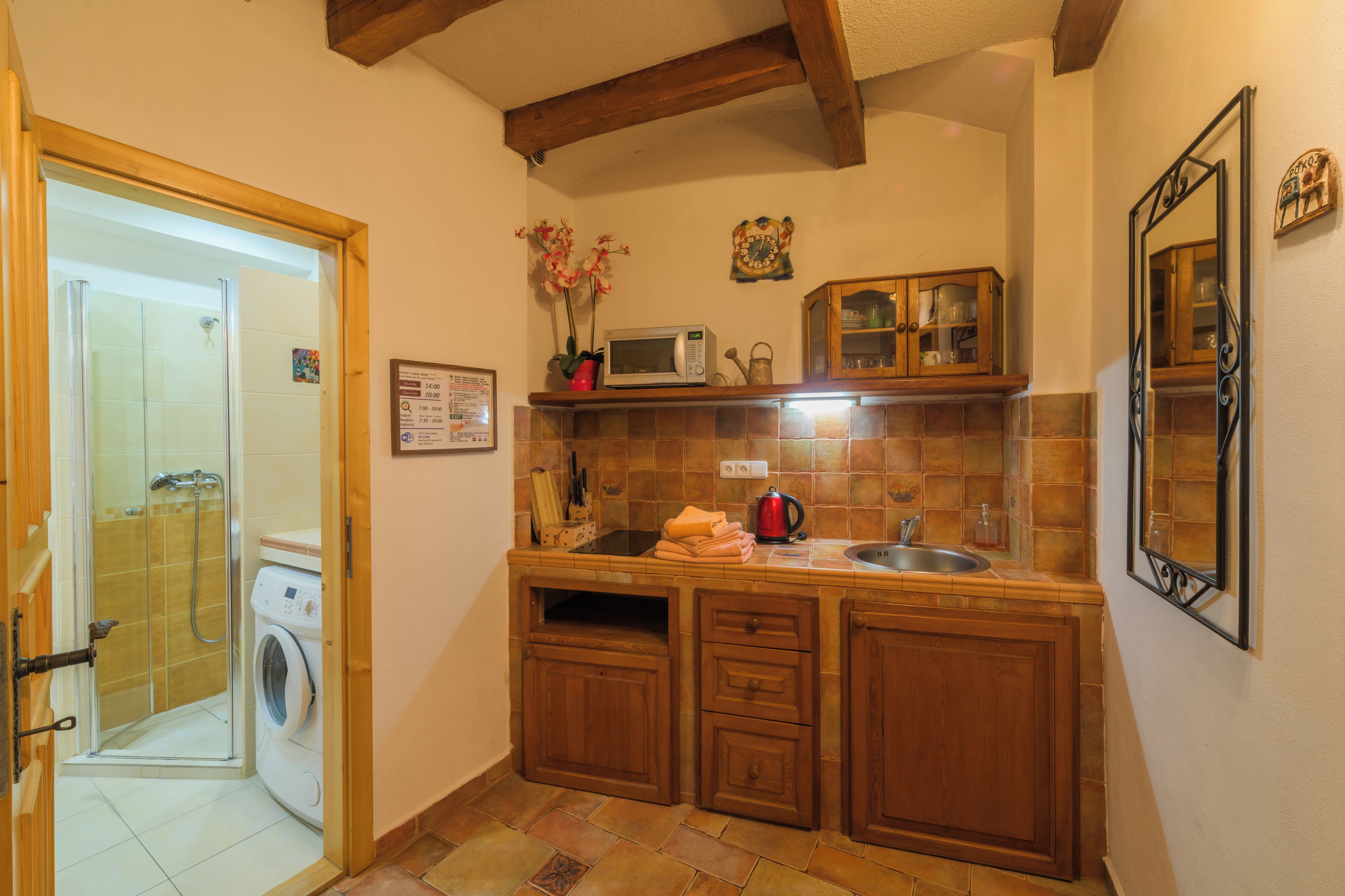 Una cocina compacta con lavadora, armarios de madera, microondas y un lavabo.