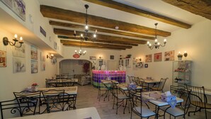 Interior de restaurante con vigas de madera a la vista, varias mesas y sillas, y decoración en las paredes.