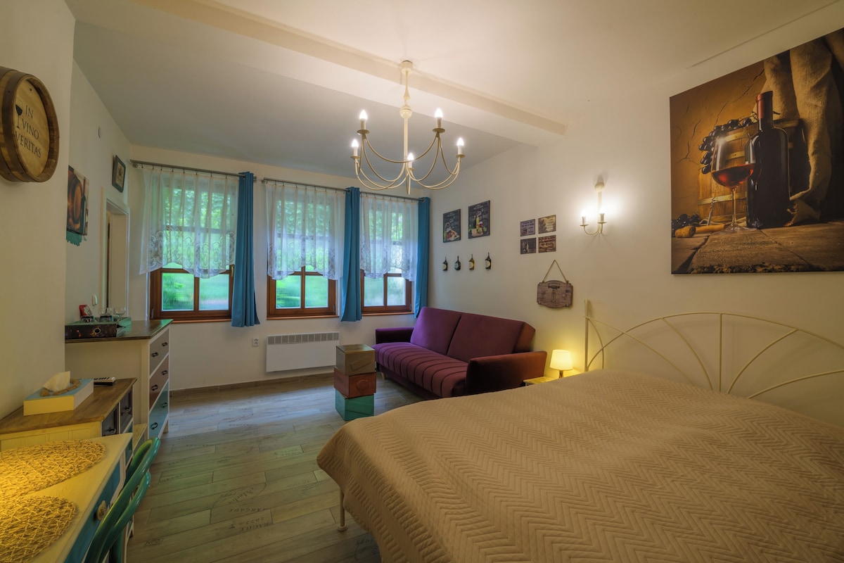 Un dormitorio con cama, cómoda, ventana con cortinas, candelabro y adornos en la pared.