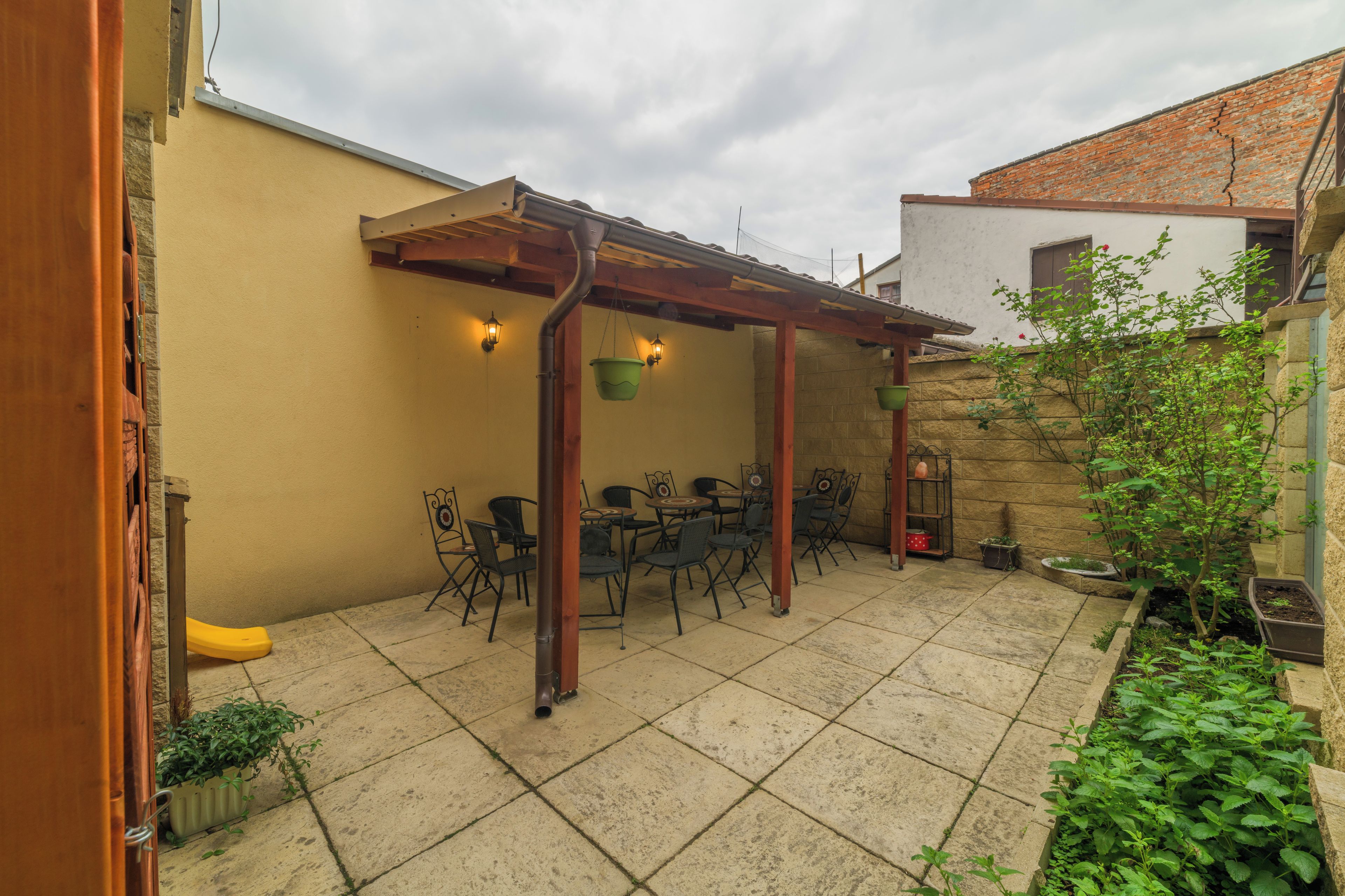 Un patio con una pérgola, mobiliario exterior y plantas en macetas.