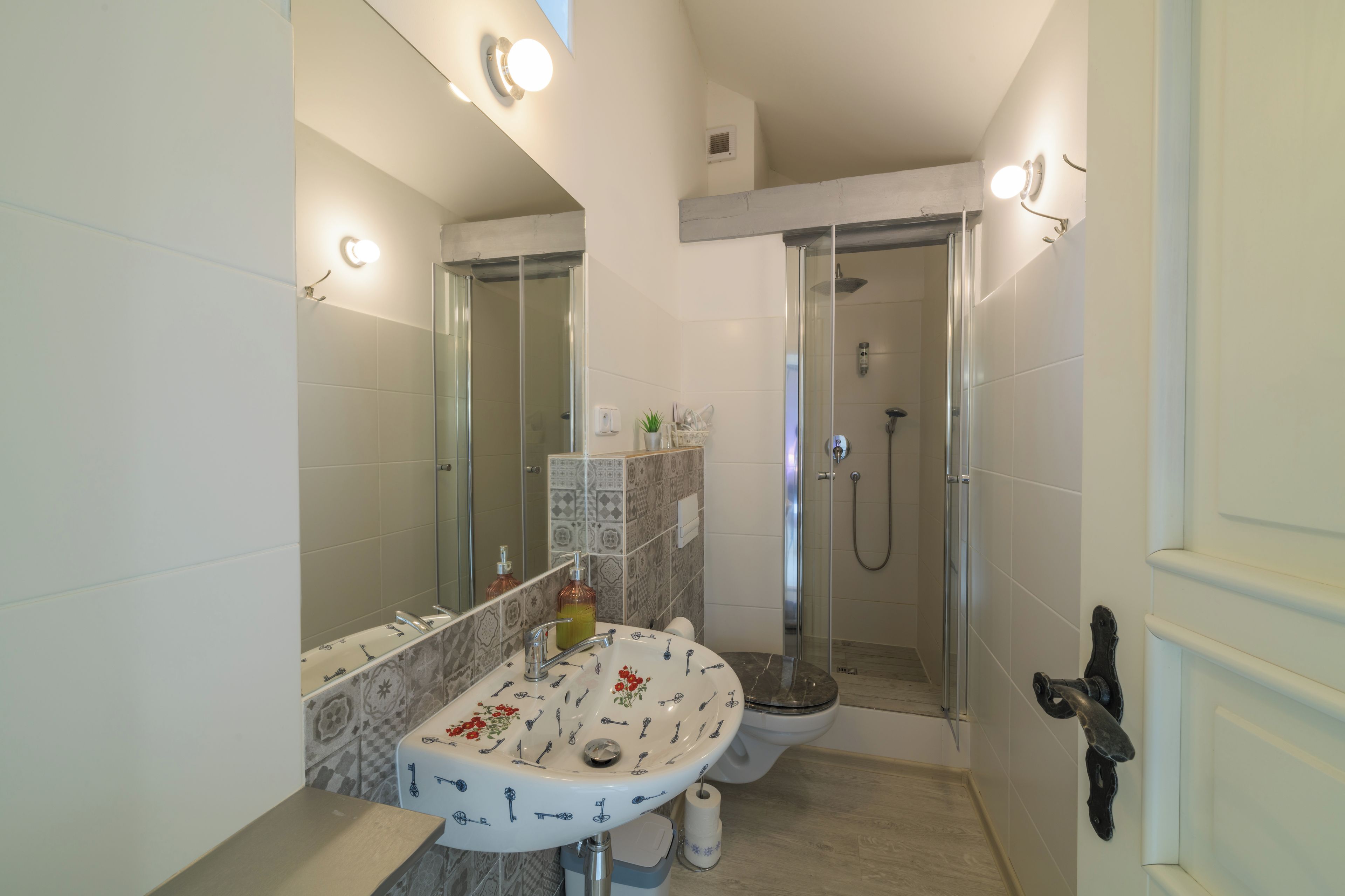 Ein modernes Badezimmer mit einer gläsernen Duschkabine, einem Waschbecken mit dekorativer Fliesenrückwand und einer Toilette.