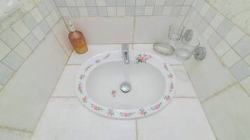 A bathroom sink with a floral design, a faucet, and a soap dispenser.