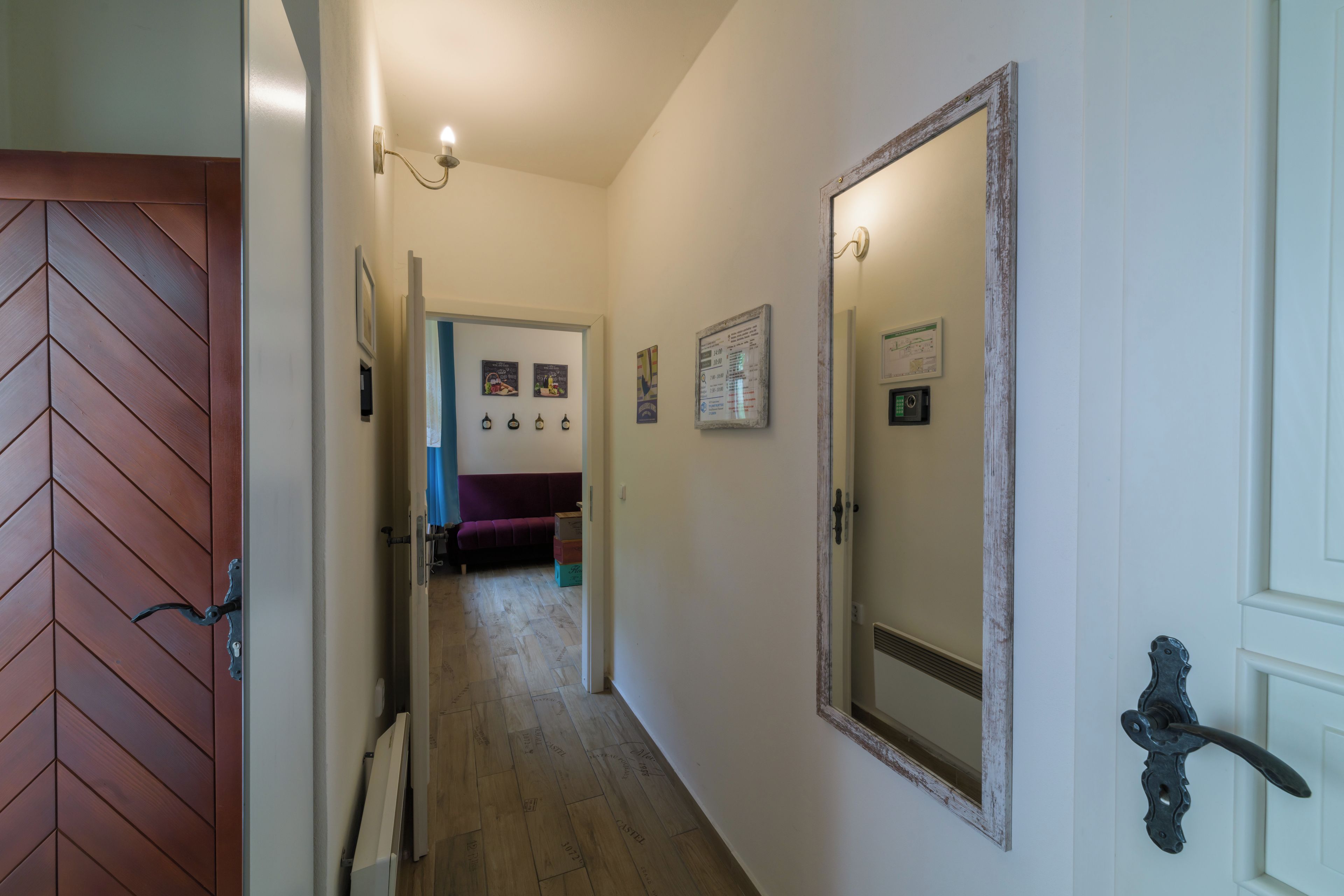 Un couloir avec une porte en bois, un miroir et un canapé violet.