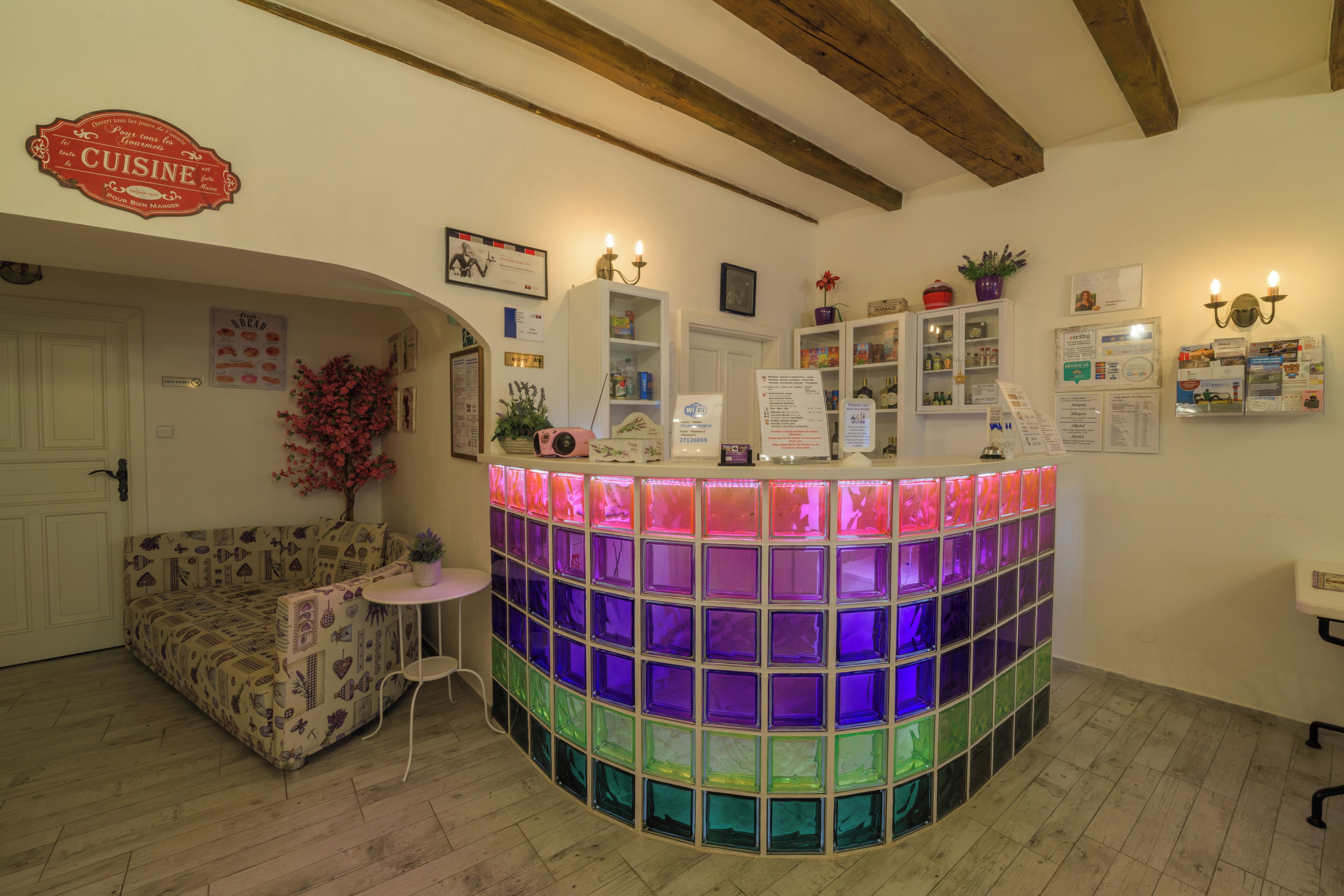 Un espace d’accueil agrémenté d’une cloison en verre aux couleurs vives, d’un canapé, d’une petite table, ainsi que de divers panneaux et éléments de décoration sur les murs.