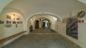 Un pasillo con techos abovedados, una escalera y varias decoraciones en las paredes, incluyendo un letrero de bienvenida y una señal de 'alto'.