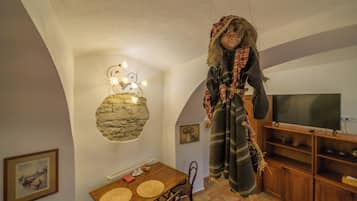 Et værelse med et spisebord, stole, et fjernsyn og en pynteting hængende på væggen.