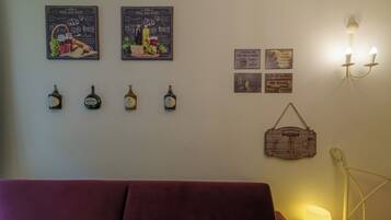 A room with a red sofa, wall-mounted wine bottles, and various posters.
