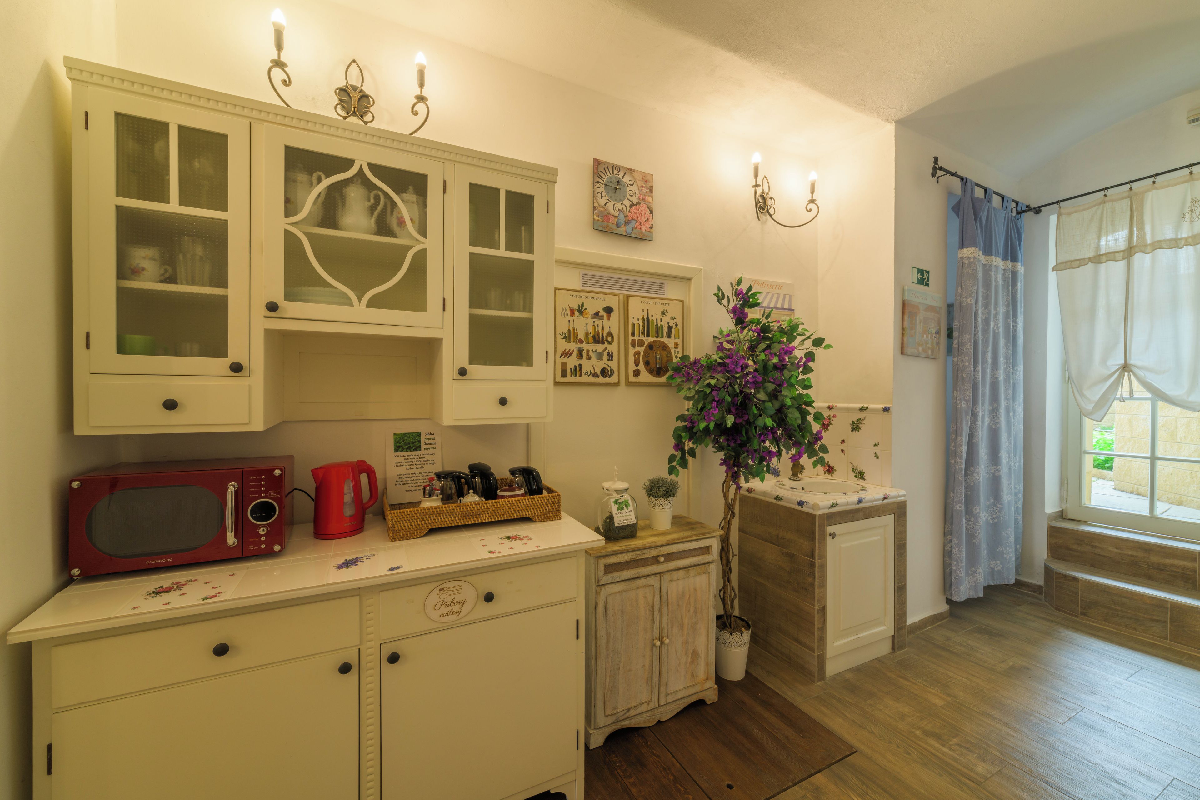 A kitchen with white cabinets, a red microwave, and a potted plant.