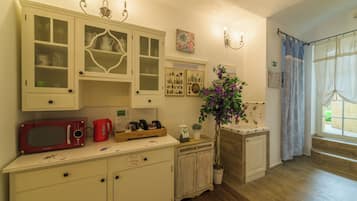 Una cocina con armarios blancos, un microondas rojo y una planta en maceta.