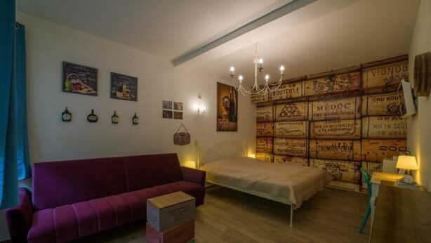Un dormitorio con una cama, un sofá rojo, una araña y una pared decorada con carteles antiguos.