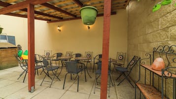 Un patio al aire libre con mesas y sillas de metal, un colgante de luz y una pared de piedra.