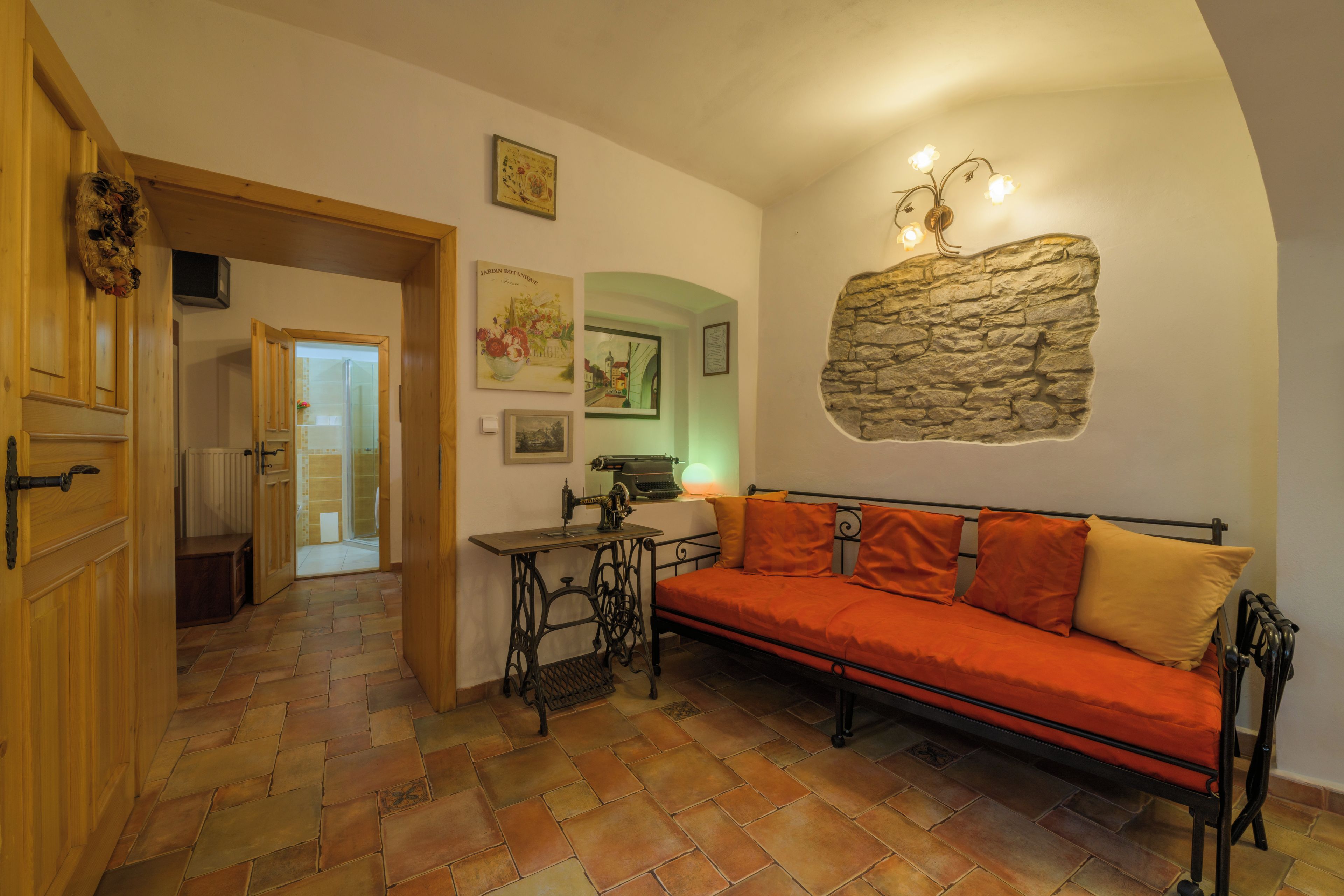 Una habitación acogedora con una pared de piedra decorativa, una máquina de coser antigua y un sofá rojo.