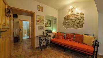 Una habitación acogedora con una pared de piedra decorativa, una máquina de coser antigua y un sofá rojo.