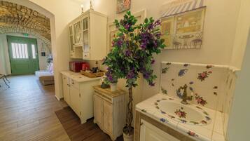 Una cocina con suelo de madera, una puerta verde, un armario blanco y una planta en maceta.