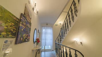 Una escalera con barandillas metálicas decorativas, un cartel de Wi-Fi instalado en la pared y un cuadro.