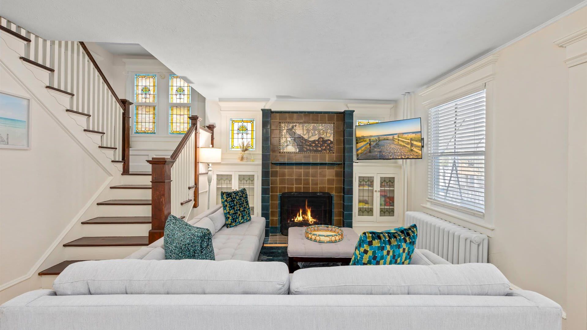 A living room with a fireplace, a staircase, and a TV mounted on the wall.