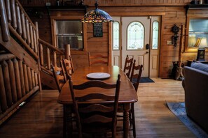 Ein Holzespeisesaal mit Stühlen, einer farbigen Glasleuchte und einer Holztreppe.