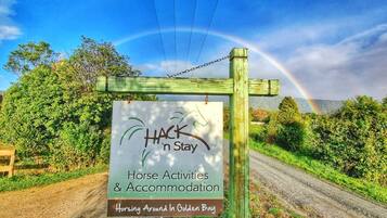 A sign for 'HACK 'n Stay' offering horse activities and accommodation in Golden Bay.
